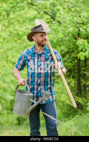 Coppia guy cappello da cowboy con annaffiatoio e pala. Arbor Day. La piantagione di alberi. Impegno e responsabilità. Concetto di agricoltura. La semina in giardino. La piantumazione di alberi di tradizione. La coltivazione di piante. Foto Stock