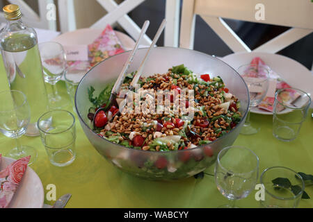 Grande ciotola di prodotti freschi e salutari e insalata di fatti in casa su un tavolo. Il include insalata di verdure fresche a foglia verde, pomodori e un sacco di semi tostati. Yummy! Foto Stock