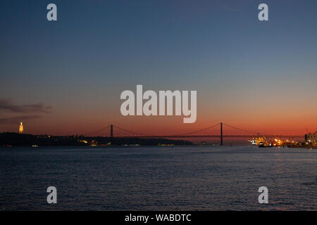 Tramonto sul fiume Tago (Rio Tejo) e il 25 de Abril Bridge (Ponte 25 de abril), a Lisbona, Portogallo Foto Stock