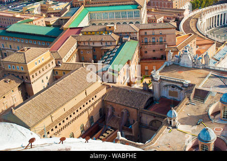 Vista di una parte di Piazza San Pietro (Piazza San Pietro) e molte colonne fra molti tetti di colore arancione e piccole torri in Vaticano, Italia. Accogliente cortile. Foto Stock
