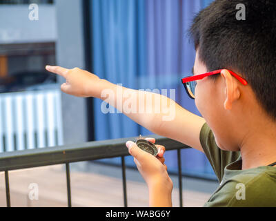 Asia boy bussola di contenimento e rivolto verso il bersaglio. Foto Stock