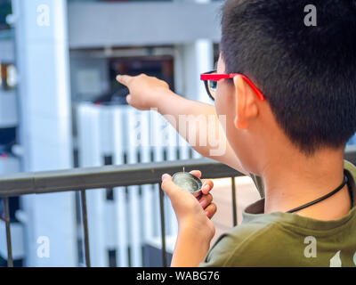 Asia boy bussola di contenimento e rivolto verso il bersaglio. Foto Stock