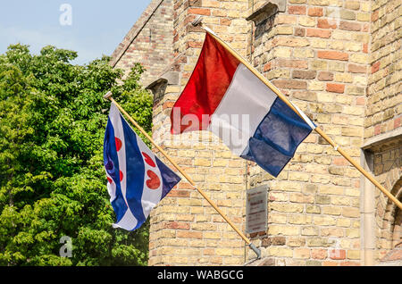 Franeker, Paesi Bassi, 27 Luglio 2019: le bandiere dei Paesi Bassi e della provincia di Fryslan fianco a fianco sulla facciata della chiesa Martini Foto Stock