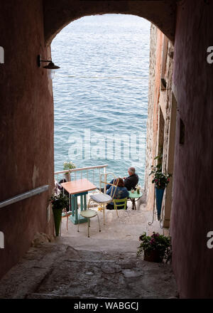 Vista in elevazione del giovane relax nel bar sulla spiaggia rocciosa, Rovigno, Istria, Croazia. Foto Stock