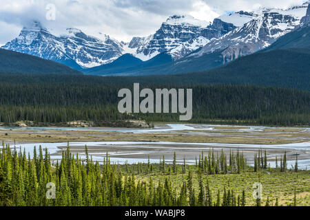 La molla sulla Valle del fiume - La luce del sole che splende attraverso nuvole temporalesche nella Valle Nord del Fiume Saskatchewan alla base delle vette innevate, il Parco Nazionale di Banff. Foto Stock