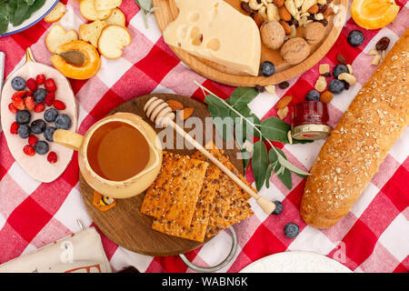 Elegante pic nic sul prato verde. Cornetti freschi e una teiera con il tè su un copriletto vicino a una femmina di vimini hat. Instagram contenuto. Foto Stock