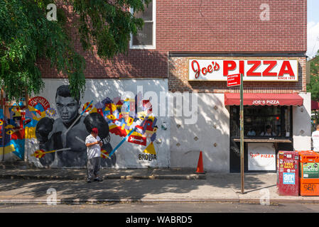 Pizza USA, vista in estate di Joe's Pizza shop e un dipinto di Muhammad Ali in una strada a Williamsburg, in New York City, Stati Uniti d'America Foto Stock