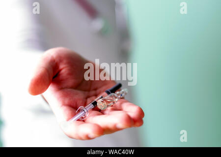 Il medico tiene fuori la siringa e fiala nella sua mano. Cure mediche concetto. Messa a fuoco selettiva Foto Stock