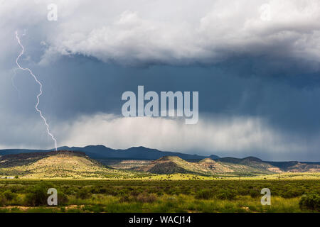 Temporale con fulmine e luce solare su montagne lontane vicino a Grants, New Mexico, USA Foto Stock