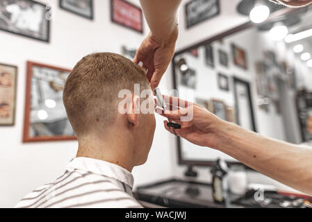 Barbiere fa un taglio di capelli alla moda e di stile per il client in un salone di bellezza. Foto Stock