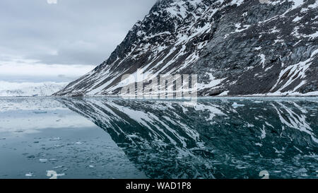 Parzialmente una montagna innevata è riflessa nelle acque artiche Foto Stock