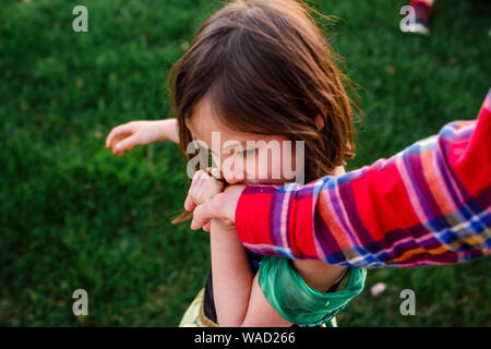 Al di sopra di vista di una ragazza piccola dolce holding controllante la mano e baciare esso Foto Stock