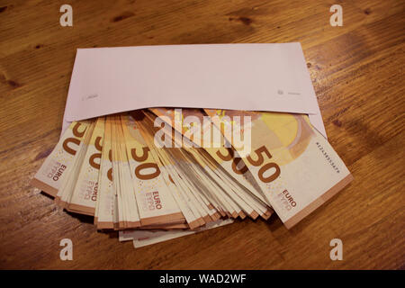 Corrompere e concetto fiscale. 50 le banconote in euro di cadere fuori della busta bianca Foto Stock