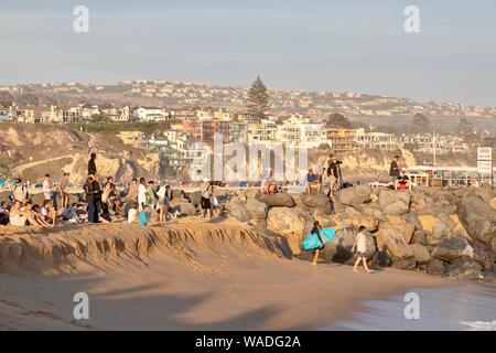 Gli spettatori presso il cuneo di Newport Beach in California a guardare la gente bodyboarding e surf Foto Stock