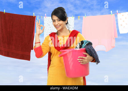 Woman drying clothes and showing ok sign Stock Photo