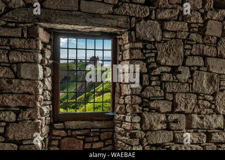 Guardando attraverso una finestra in un muro di pietra per il castello di Dunottar, Scozia Foto Stock