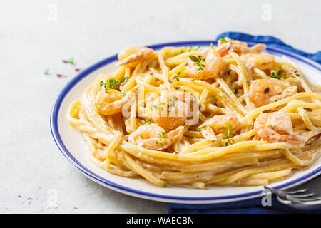 La pasta di gamberetti con la panna e le erbe in una piastra bianca. Foto Stock