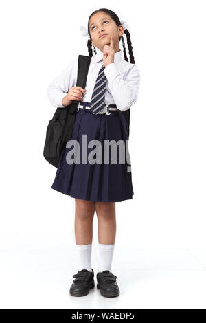 Schoolgirl in piedi con zaino e pensare Foto Stock