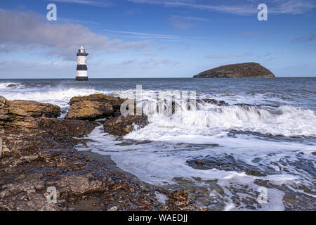 Faro e Puffin Island al punto Penmon, Anglesey, Galles del Nord in una giornata di vento con onde che si infrangono sulla foreshore Foto Stock