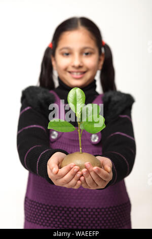 Ragazza che tiene una piccola pianta Foto Stock