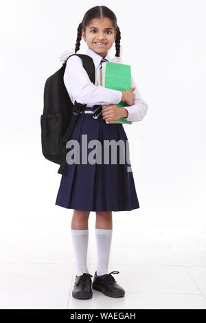 Schoolgirl in piedi con la borsa e puntamento Foto Stock