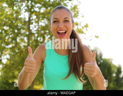 Super donna!!! Ritratto di vincitore ragazza mostra Thumbs up. Positivo fitness sorridente donna sana all'aperto. Foto Stock