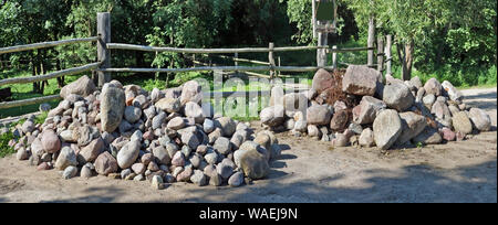 Due grandi pile di massi di granito e pietre giacciono nella foresta vicino a un recinto di villaggio Foto Stock