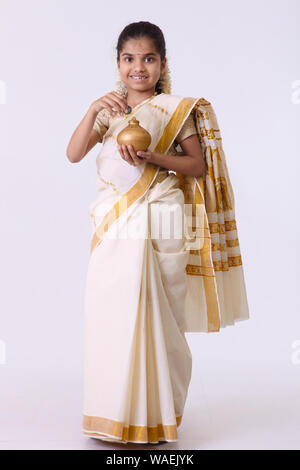 Girl pretending to be a housewife and inserting a coin into a piggy bank Stock Photo