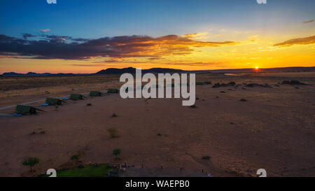 Il tramonto sopra i piccoli chalets di una desert lodge vicino al Sossusvlei in Namibia Foto Stock