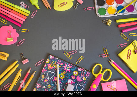 Colorato di forniture scolastiche su sfondo scuro, torna al concetto di scuola. Vista da sopra con copia spazio. Foto Stock