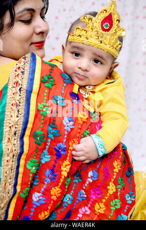 Immagine di una madre mentre tiene il suo bambino Krishna celebrando Janmashtami festival. Isolato su sfondo bianco. Foto Stock