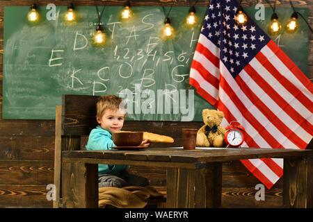 Il patriottismo e la libertà. Little Boy mangiare pane a bandiera americana a conoscenza giorno. Felice giorno di indipendenza degli Stati Uniti d'America. Scuola kid alla lezione 4 di luglio Foto Stock