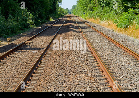 I binari della ferrovia su traversine di cemento e letto di zavorra Foto Stock