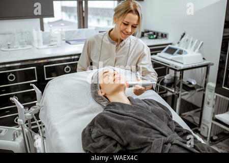 Cosmetologo femmina rendendo mesoterapia ossigeno ad una donna presso il lussuoso salone di bellezza. Concetto di un professionista del trattamento del viso Foto Stock