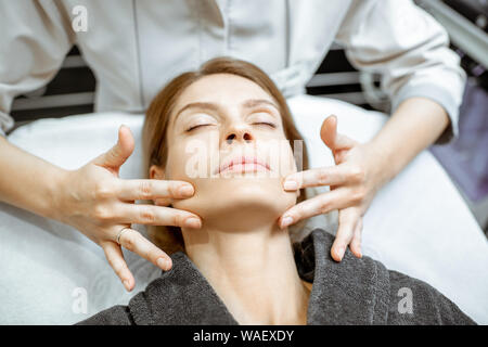 Donna che fa il massaggio del viso presso il salone di bellezza. Concetto di linfodrenaggio terapia Foto Stock