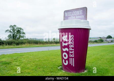 Un grande iconico Costa Coffee Cup accanto alla strada nel Lake District inglese Foto Stock