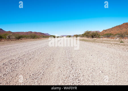 Una strada sterrata attraverso Damaraland scompare oltre l'orizzonte Foto Stock