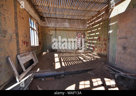 Il deserto recupera lentamente una casa abbandonati nella città fantasma di Kolmanskop, Namibia Foto Stock