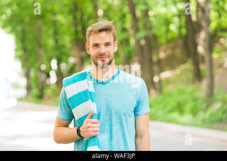 Sano e attivo. Blonde l'uomo. Uomo bello indossare casual tshirt con asciugamano sul paesaggio naturale. Uomo con unshaved viso capelli e taglio di capelli alla moda. Uomo caucasico sul giorno di estate. Foto Stock