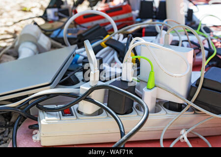 Un mazzetto di gadget di carica, dispositivi elettronici, fili disordinati. dipendenza da energia elettrica Foto Stock