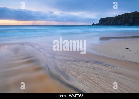 L'acqua scorre su strutture bizzarre sulla spiaggia sabbiosa, pioggia nuvole sopra il mare, Dalmore Beach, isola di Lewis, Scozia Foto Stock