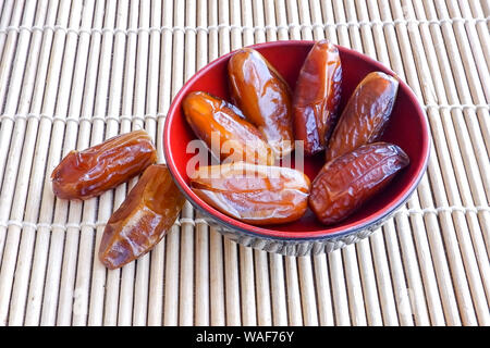 Gruppo di frutta di Phoenix in rosso coppa sul tappetino di bambù. Foto Stock