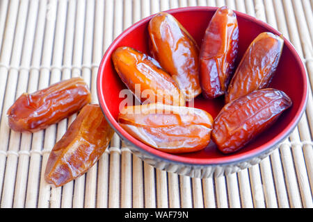 Gruppo di frutta di Phoenix in rosso coppa sul tappetino di bambù. Foto Stock