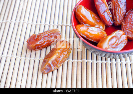 Gruppo di frutta di Phoenix in rosso coppa sul tappetino di bambù. Foto Stock