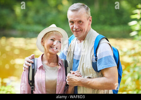 Ritratto di escursionisti senior con zaini sorridente alla telecamera mentre in piedi in natura all'aperto Foto Stock