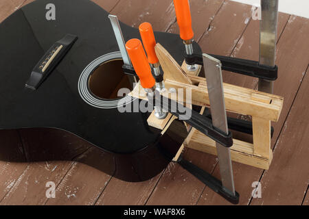 La riparazione di una chitarra e il servizio di assistenza - Riparazione rottura di serraggio della scheda del suono di chitarra acustica di sfondo di legno Foto Stock