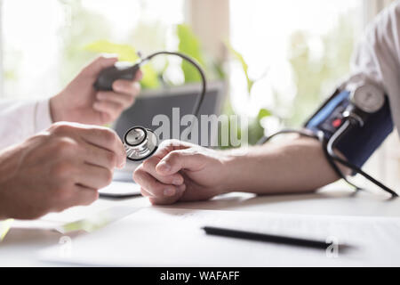 Medico controllando la pressione del sangue di un paziente Foto Stock