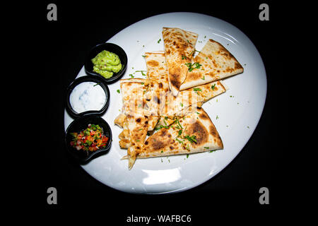 Un tradizionale pollo quesadilla con ripieno di formaggio e accompagnato con un trio di salse Foto Stock