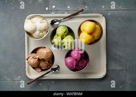 Un assortimento di sapori e colori di gourmet gelato italiano servito sul tavolo in acciaio. Mango, cioccolato, Verde matcha ice cream Foto Stock