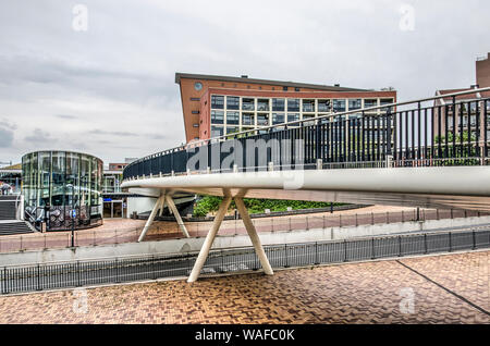 Helmond, Paesi Bassi, 16 agosto 2019: il lato ovest della piazza della stazione con un ponte per pedoni e ciclisti attraversando la trafficata Stazione St Foto Stock